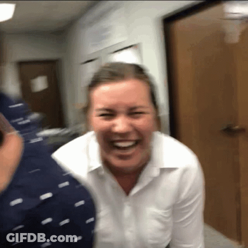 A Woman In A White Shirt Is Laughing With A Man In A Blue Shirt GIF