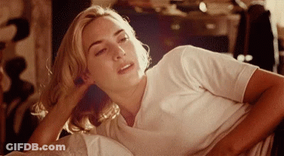 A Woman In A White Shirt Is Laying Down With Her Head On Her Hand GIF