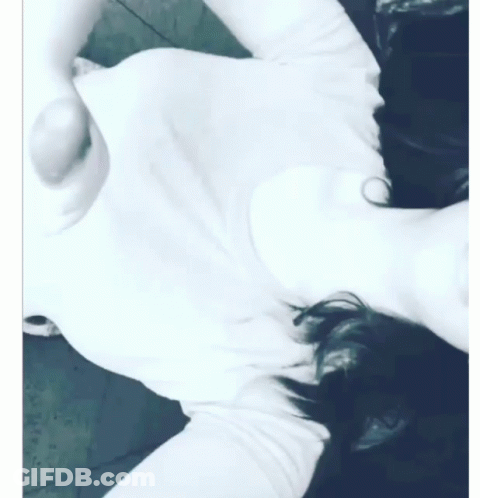 A Woman In A White Shirt Is Laying On Her Back GIF