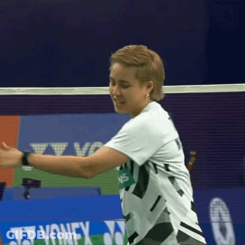 A Woman In A White Shirt Is Playing Badminton In Front Of A Yonex Advertisement GIF