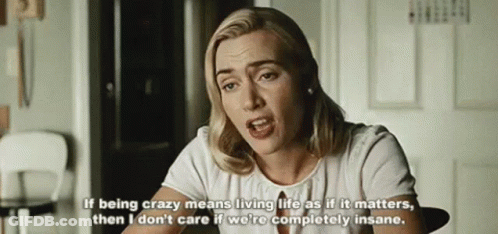 A Woman In A White Shirt Is Sitting At A Table With A Quote On It . GIF