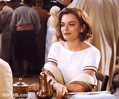 A Woman In A White Shirt Is Sitting At A Table With A Teapot In Front Of Her . GIF