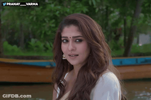 A Woman In A White Shirt Is Smiling And Waving In Front Of A Boat With The Hashtag Pranay_varma GIF