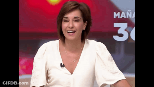A Woman In A White Shirt Is Smiling In Front Of A Sign That Says Mañana GIF