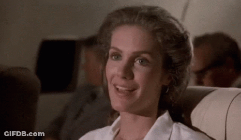 A Woman In A White Shirt Is Smiling While Sitting On A Plane GIF