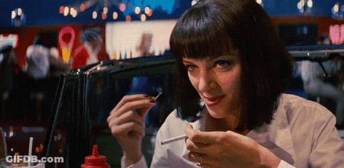 A Woman In A White Shirt Is Smoking A Cigarette In A Diner GIF