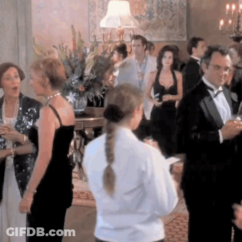 A Woman In A White Shirt Is Standing In A Crowd GIF