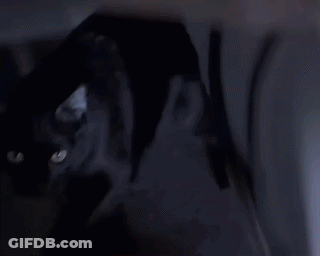 A Woman In A White Shirt Is Standing In A Dark Room . GIF