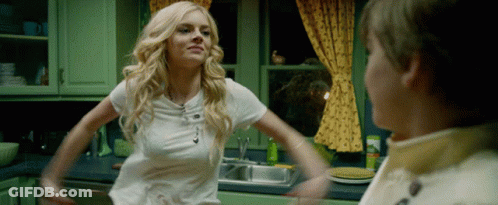 A Woman In A White Shirt Is Standing In A Kitchen With Her Arms Outstretched GIF