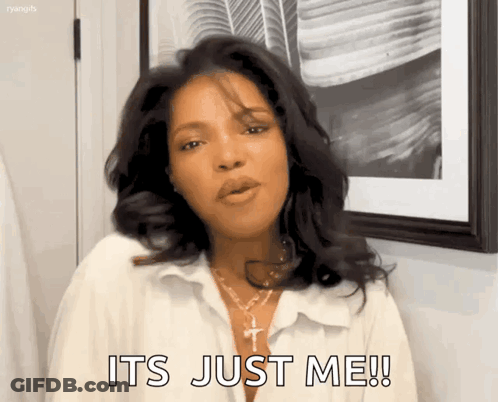 A Woman In A White Shirt Is Standing In Front Of A Picture Frame And Says It 'S Just Me ! GIF