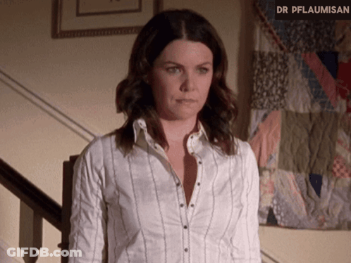 A Woman In A White Shirt Is Standing In Front Of A Quilt That Says Dr Pflaumisen GIF