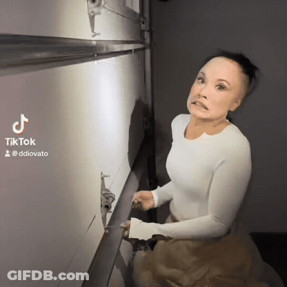 A Woman In A White Shirt Is Standing In Front Of A Wall With A Tiktok Watermark GIF
