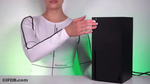 A Woman In A White Shirt Is Standing Next To A Black Xbox Console . GIF