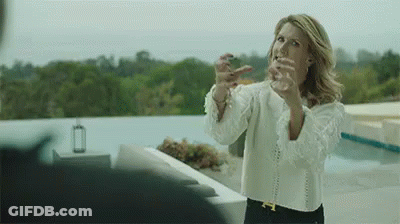 A Woman In A White Shirt Is Standing On A Balcony With Her Arms Outstretched . GIF