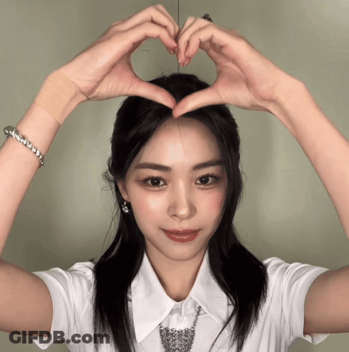 A Woman In A White Shirt Making A Heart With Her Hands GIF