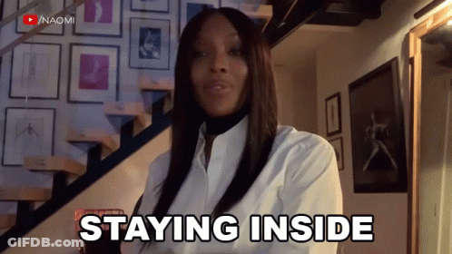 A Woman In A White Shirt Says " Staying Inside " In Front Of A Staircase GIF