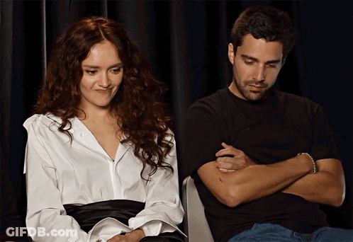 A Woman In A White Shirt Sits Next To A Man In A Black Shirt GIF