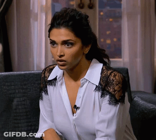 A Woman In A White Shirt With Black Lace Sleeves Looks Surprised GIF