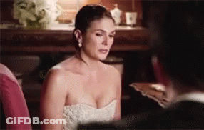 A Woman In A White Strapless Dress Is Sitting Next To A Man In A Suit . GIF