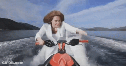 A Woman In A White Suit Is Riding A Jet Ski In The Water GIF