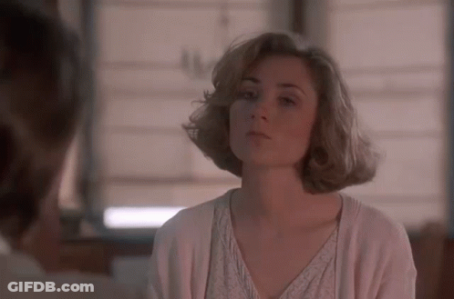 A Woman In A White Sweater Is Looking At A Man In A Room . GIF