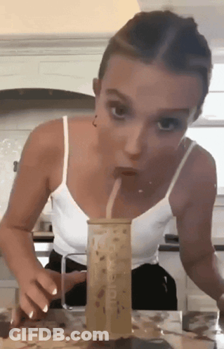 A Woman In A White Tank Top Drinks Through A Straw From A Cup That Says Mcdonald 'S On It GIF