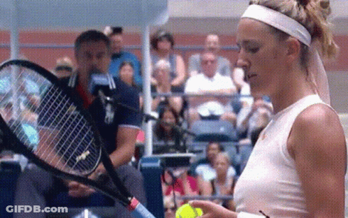 A Woman In A White Tank Top Is Holding A Tennis Racquet And A Ball . GIF