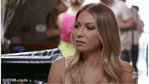 A Woman In A White Tank Top Is Sitting In A Room With A Group Of People . GIF