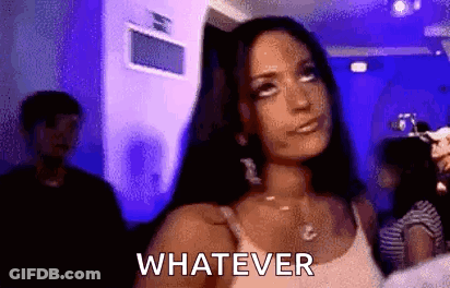 A Woman In A White Tank Top Is Standing In A Room With A Blue Light And Says Whatever . GIF