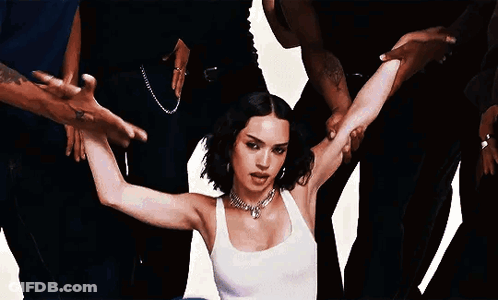 A Woman In A White Tank Top Is Surrounded By A Group Of People . GIF