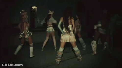A Woman In A White Top And Blue Gloves Is Dancing In Front Of Two Other Women . GIF