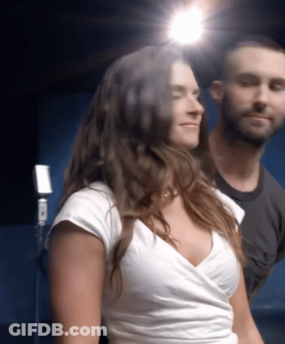 A Woman In A White Top Is Standing Next To A Man GIF