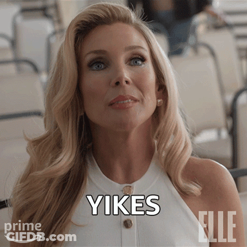 A Woman In A White Top With The Word Yikes Written On Her Face GIF