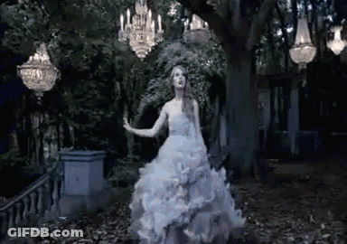 A Woman In A White Wedding Dress Is Dancing In A Dark Forest . GIF
