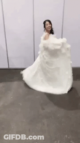 A Woman In A White Wedding Dress Is Dancing On A Floor . GIF