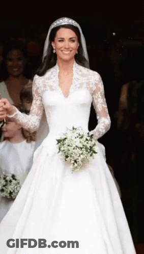A Woman In A White Wedding Dress Is Holding A Bouquet Of White Flowers . GIF