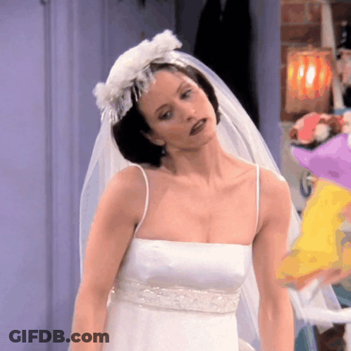 A Woman In A White Wedding Dress With A Veil GIF