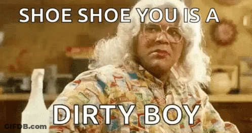A Woman In A Wig And Glasses Is Sitting At A Table With A Bottle Of Spray . GIF