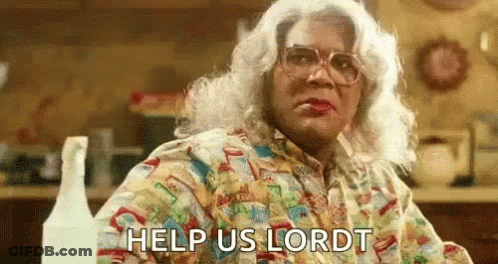 A Woman In A Wig And Glasses Is Sitting At A Table With The Words `` Help Us Lord '' Written On Her Face . GIF