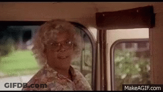 A Woman In A Wig And Glasses Is Standing In A Bus . GIF