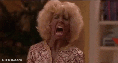 A Woman In A Wig Is Screaming With Her Mouth Open . GIF