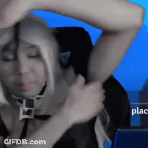 A Woman In A Wig Is Sitting In A Chair With A Sign That Says Place In The Background GIF