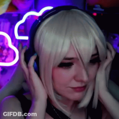 A Woman In A Wig Is Wearing Headphones In Front Of A Purple Neon Sign . GIF