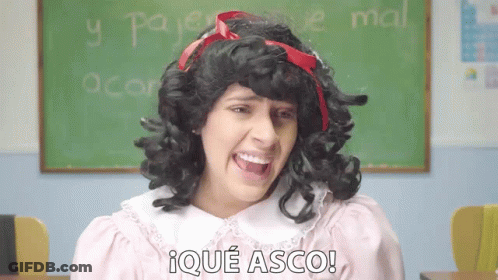 A Woman In A Wig Says Ique Asco In Front Of A Green Board GIF