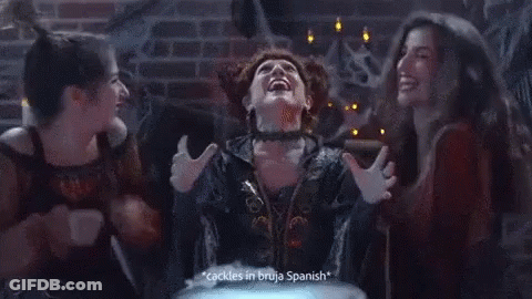 A Woman In A Witch Costume Says " Cackles In Bruja Spanish " While Two Other Women Look On GIF