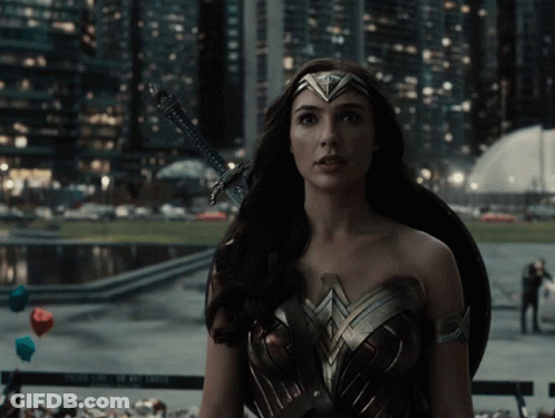 A Woman In A Wonder Woman Costume Holds A Sword And Shield GIF