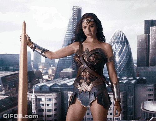 A Woman In A Wonder Woman Costume Holds A Sword In Front Of A City Skyline GIF