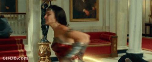 A Woman In A Wonder Woman Costume Is Holding A Lightning Bolt GIF