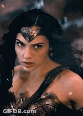 A Woman In A Wonder Woman Costume Is Looking At The Camera GIF