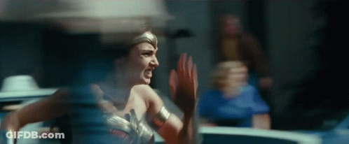 A Woman In A Wonder Woman Costume Is Running And Screaming In A Room . GIF